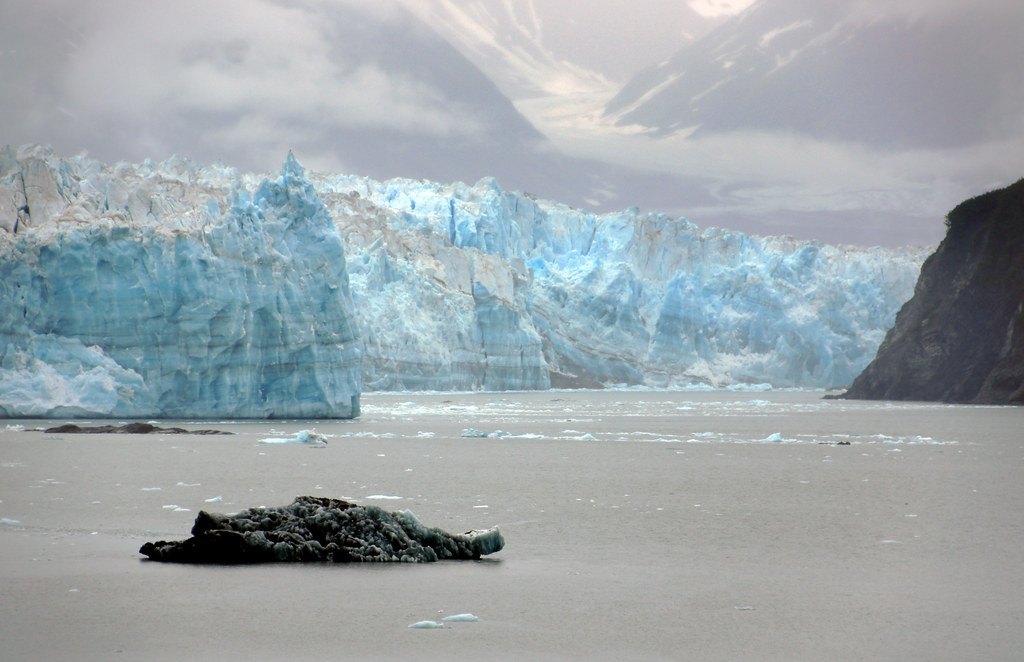The blue ice face of Hubbard Glacier in Alaska, rising above grey water