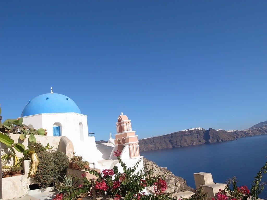 A blue church dome and bell tower above the sea on Santorini, Greece